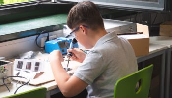 Zu sehen ist ein Junge, der gerade elektronische Komponenten zusammen lötet.