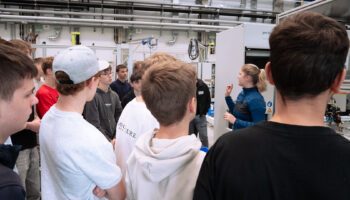Zu sehen sind Schüler des Anton-Bruckner-Gymnasiums, die gerade von einer Auszubildenden der Sonplas GmbH ihren Ausbildungsberuf vorgestellt bekommen.