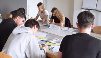 Die neuen Auszubildenden sitzen an einem Tisch und bereiten sich gerade für ein Kennenlern-Spiel vor.