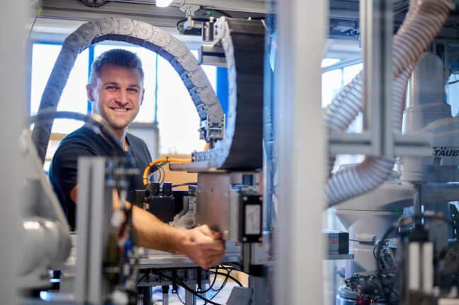 Sonplas Mitarbeiter montiert etwas und schaut in die Kamera