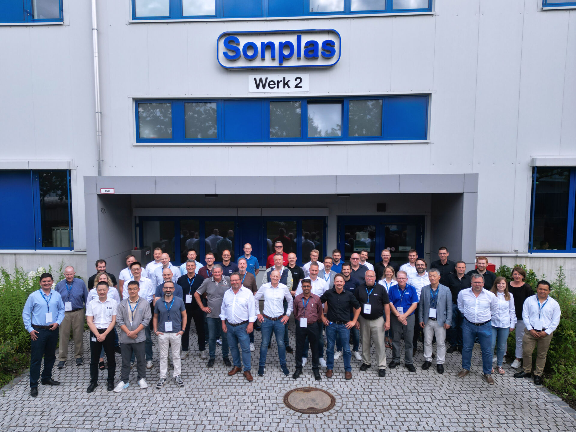 Eine Gruppe von knapp 50 Menschen seht vor dem Firmengebäude von Sonplas. Das Logo ist im Hintergrund zu sehen. Die Gruppe besteht aus Vertreterinnen und Vertretern von Sonplas sowie weltweiten Service- und Vertriebspartnern.