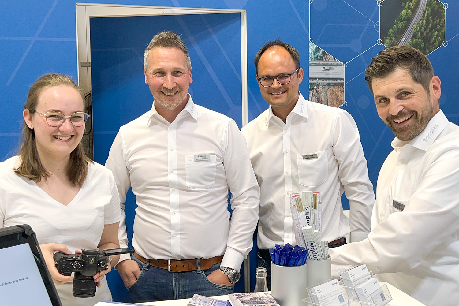 Vier Sonplas-Mitarbeitende posieren zum Gruppenfoto auf einer Messe, sie lächeln in die Kamera.