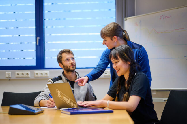 Drei Sonplas Mitarbeiter beraten sich und schauen in einen Laptop