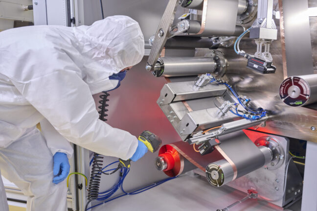 Sonplas Mitarbeiter in Schutzkleidung steht vor einem Lasernotcher und scannt das Material an der Abwicklung