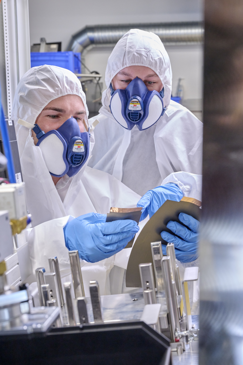 Zwei Personen stehen vor dem Lasernotcher und schauen sich Elektrodenblätter an