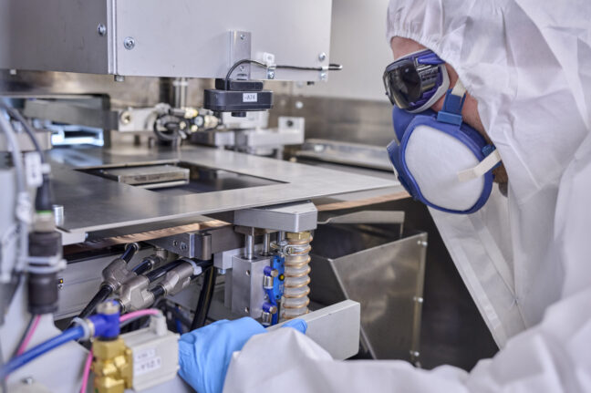 Person in Schutzausrüstung steht vor der Laserstation und schaut diese an