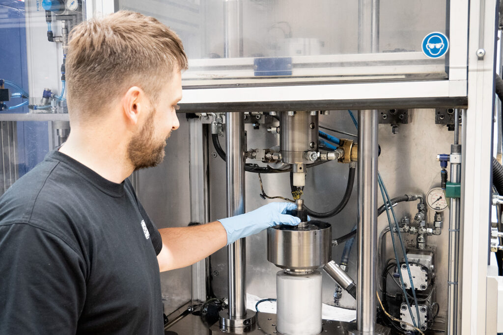 Sonplas Mitarbeiter steht vor einem Entwicklungsprüfstand und befüllt etwas