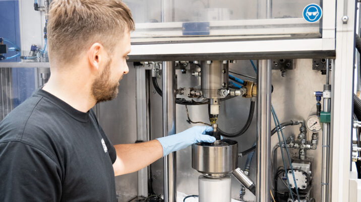 Sonplas Mitarbeiter steht vor einem Entwicklungsprüfstand und befüllt etwas